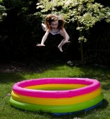 skacząca do kolorowego dmuchanego basenu dziewczynka